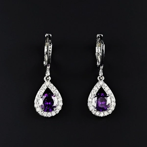 Détail de boucles d'oreilles pendantes en forme de goutte avec gemme violette et halo