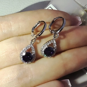 Vue macro des boucles d'oreilles goutte avec pierre violette et serti de cristaux