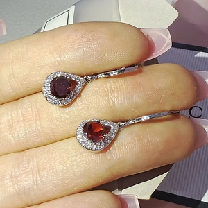 Détail de boucles d'oreilles larmes rouges avec pierres poires et contour en cristaux