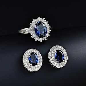 Elegantes Schmuckset mit blauem ovalem Edelsteinring und passenden Ohrsteckern auf Schwarz