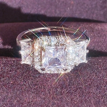 Macro shot of silver ring with square halo stones on a deep purple velvet background