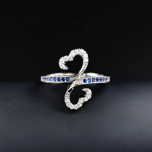 Macro shot of silver ring featuring interlocking hollow hearts and deep blue gemstones