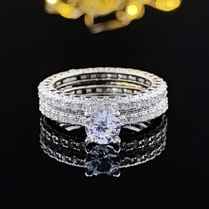 Set de anillos de lujo en plata con piedra redonda y banda pavé sobre fondo negro