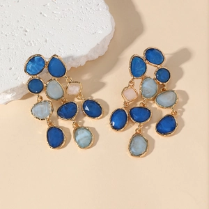 Luxurious long tassel earrings with colorful resin drops and gold base on a stone background