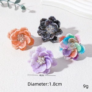 Detailed view of floral resin rings with pearl centers on a textured stone surface