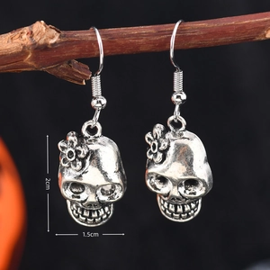 Détail de boucles d'oreilles tête de mort vintage avec fleur sur branche rustique