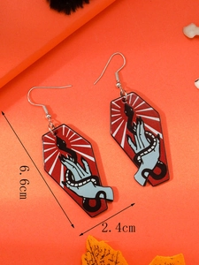 Macro shot of coffin-shaped acrylic earrings with blue hand and snake on orange background
