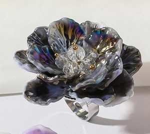Primer plano de un anillo de flor de resina 3D con pétalos morados irisados y banda plata