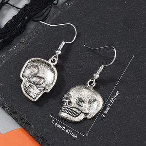 Détail de boucles d'oreilles squelette punk avec dimensions 3,8cm x 1,6cm sur pierre