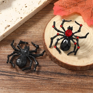 Gothic spider stud earrings with red crystals and black alloy on a rustic wood base