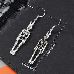 Détail de boucles d'oreilles squelette argentées vintage de 5,8 cm sur fond de roche noire