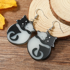 Halloween black and white cat acrylic earrings in yin yang style on wooden background