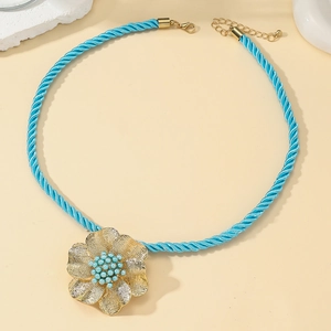 Detailansicht der hellblauen Kordelkette mit großem goldenen Blumenanhänger und Perlen