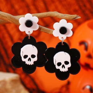 Pendientes de acrílico de Halloween con calavera y flores sobre un fondo naranja vivo