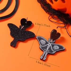 Detail view of gothic black moth acrylic earrings with glitter and eye pattern