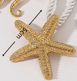 Detail eines 5cm goldenen Seestern-Anhängers mit gewebtem Seil auf neutralem Hintergrund