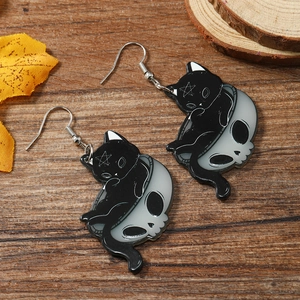 Makroaufnahme von Gothic Acryl-Ohrringen mit schwarzer Katze im Totenkopf auf Holzdekor