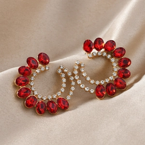 Boucles d'oreilles goutte d'or avec pierres rouges et cristaux blancs sur fond de soie