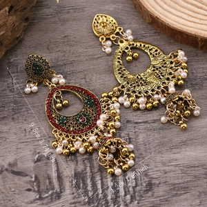 Vista macro di orecchini Jhumka vintage con strass rossi e perle bianche finemente lavorati