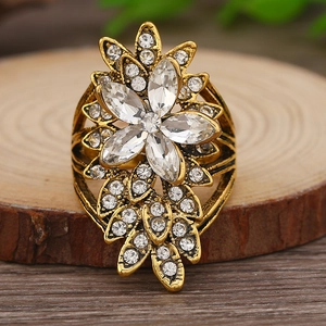 Makroaufnahme eines Vintage-Goldrings mit Marquise-Strasssteinen auf Holzsockel