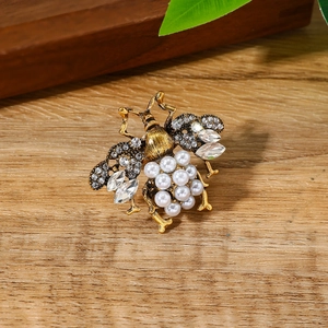 Vintage gouden bijenring met parels en strassteentjes op houten ondergrond