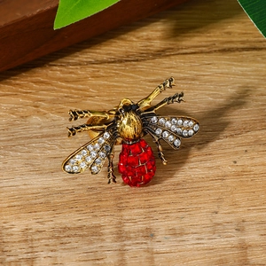 Luxe bijenring met rode edelstenen en kristallen vleugels op een houten ondergrond