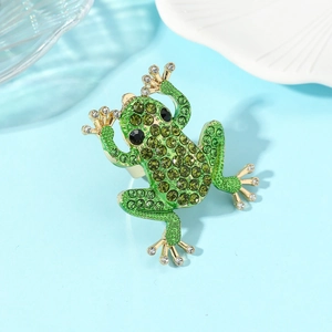 Macro-detail van een gouden kikkerring met groene strass-steentjes op een schelpplaat