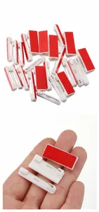 Detailed view of white plastic safety pins with red adhesive backing for DIY badges