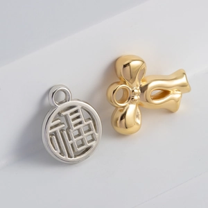 Macro shot of silver Fu character and golden knot pendants for DIY jewelry making