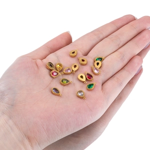 Pendentifs gouttes en strass colorés sur monture dorée présentés dans la main