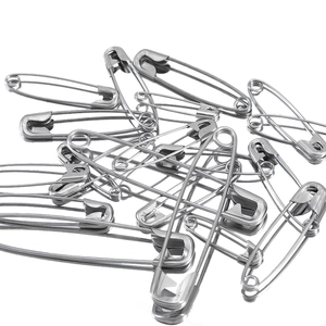 Macro shot of assorted stainless steel safety pins on white surface with reflection