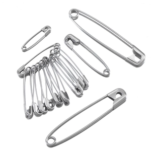 Macro shot of silver stainless steel safety pins in various sizes on white surface