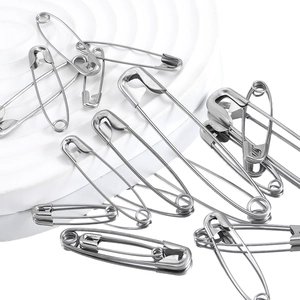 Assorted silver stainless steel safety pins in various sizes on a white platform