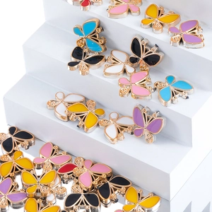 Macro detail of colorful enamel butterfly charms on a white tiered display for DIY jewelry