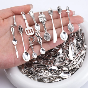 Close-up of vintage silver alloy miniature cutlery pendants for DIY jewelry making
