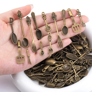 Close-up of vintage bronze cutlery charms held in hand for DIY jewelry making size scale