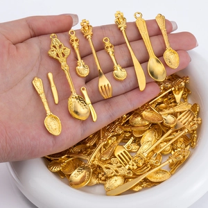 Detailed view of tiny golden alloy vintage cutlery charms including forks and spoons