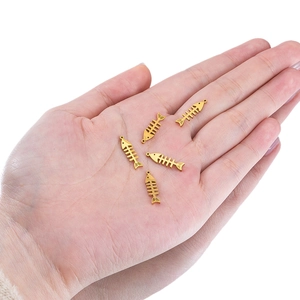 Five gold stainless steel fishbone pendants for DIY jewelry making on palm background