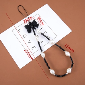 Detail of beaded phone strap featuring black beads, white pearls, and a black bow tie