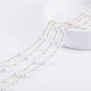 Baroque irregular pearls and gold stainless steel chain necklace draped on a white porcelain bowl
