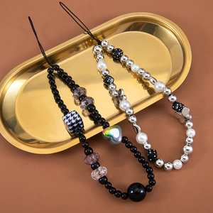 Dark aesthetic phone charms with black beads, white pearls and butterfly charms on gold tray