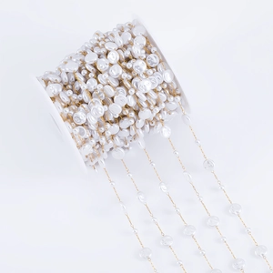 Detailed macro of baroque irregular white pearls on a gold stainless steel chain roll