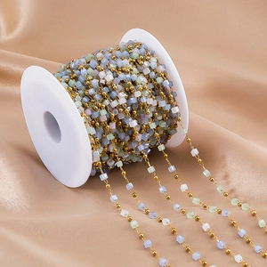 Detail of DIY bead chain with gold balls and pastel blocks on a white plastic spool