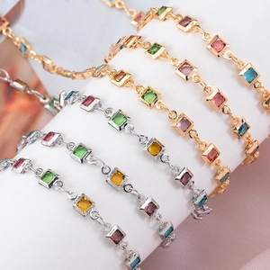Detalle de elegantes pulseras con piedras cuadradas de colores y acabado en oro y plata