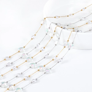 Dettaglio macro di catene DIY oro e argento con perle finte e cuori iridescenti lucidi