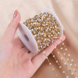 Detail of gold beads and white square pearls on a stainless steel DIY jewelry chain