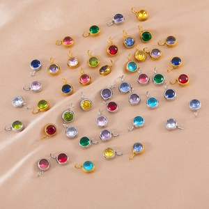 Dettaglio di ciondoli tondi in zircone colorato con montature in oro e argento lucido