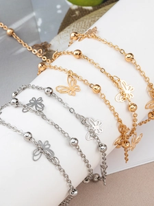 Close-up of gold and silver butterfly pendants with round beads on delicate metal chains