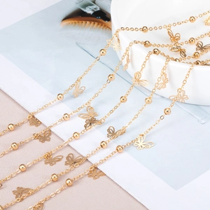 Detail of golden copper chain with solid metal beads and hollow butterfly charms for DIY