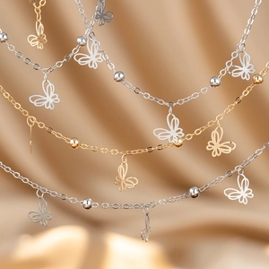 Detailed close-up of gold and silver filigree butterfly charms on delicate beaded chains